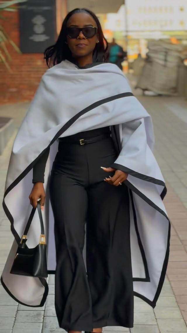 Elan By Kristen — white cape with contrast black trim over black flared trousers